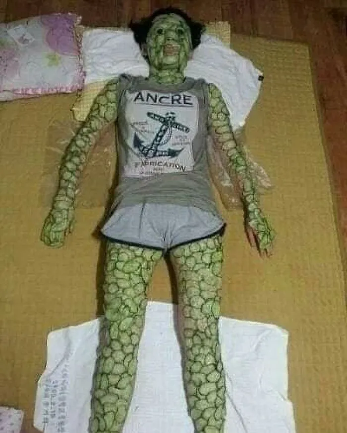 Person covered in cucumber slices wearing a grey shirt and shorts, lying on a mat, illustrating weird cursed pics.
