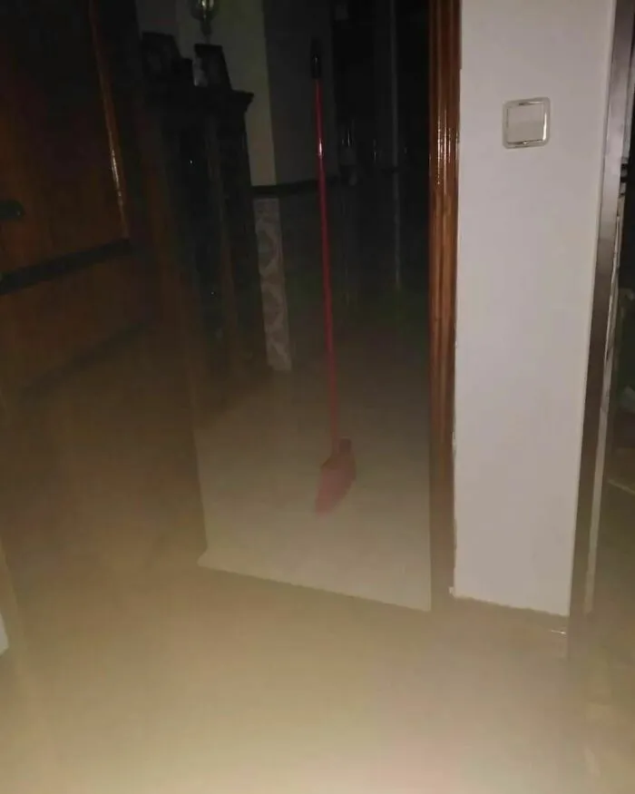 A broom standing upright in a dimly lit hallway, creating a weird atmosphere.