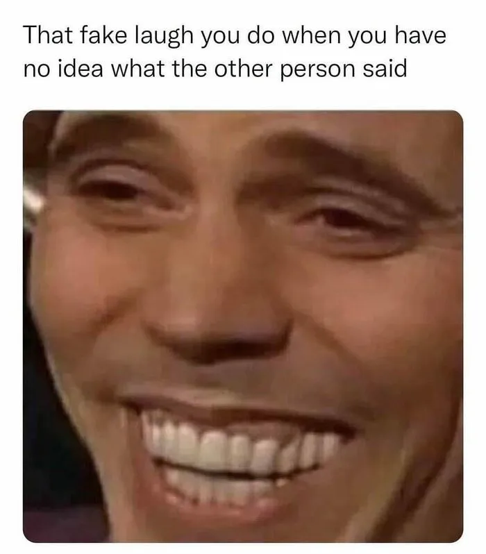 Close-up of a person with a forced smile, capturing an amusing introvert meme moment.