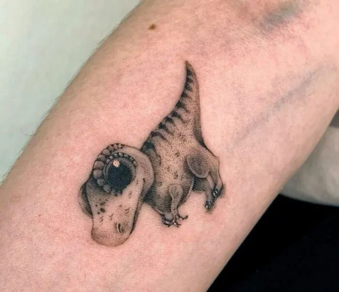Small dinosaur tattoo on forearm, showcasing a creative and perfectly executed design.