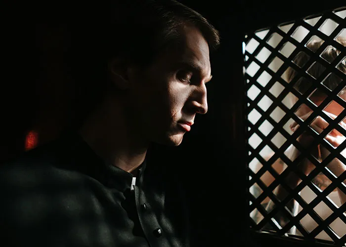 A person in a dimly lit room shares a moment of laughter, evoking a scene tied to funny jokes.
