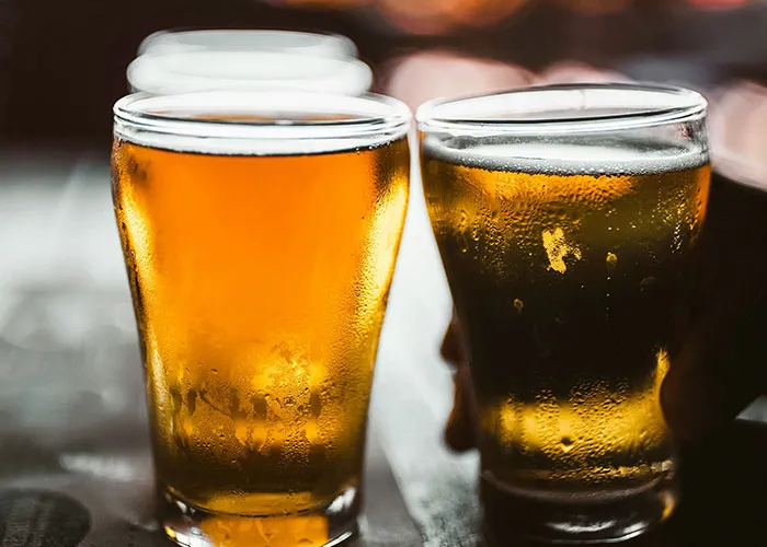 Two frosty glasses of beer reflecting soft light in a pub setting, capturing the essence of a funny joke moment.