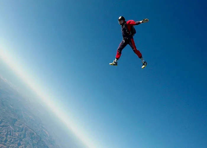 Skydiver in a red-and-blue suit freefalling against a clear blue sky, symbolizing the thrill of laughter and jokes.