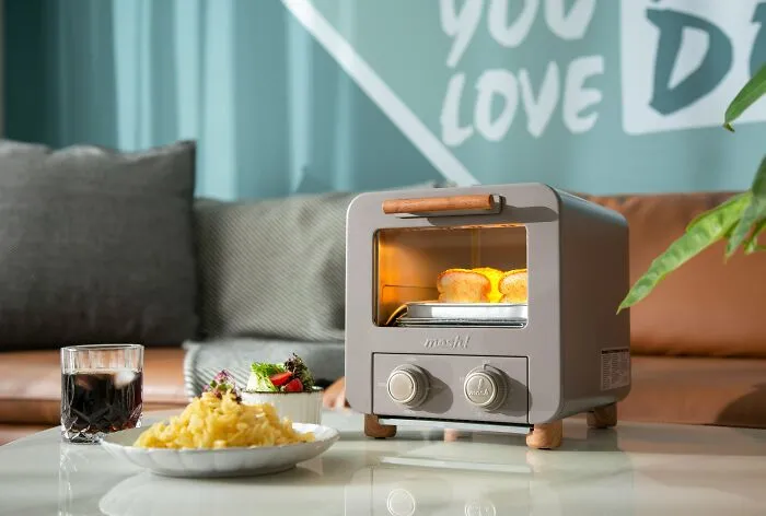 A toaster oven with a bowl of food and a glass of wine
