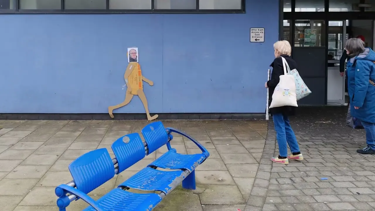 Life-Size Animated Cardboard Cut-Out Person Really Runs Round A Town. Its Head Is Changing Photos Of People Who Helped Make It Happen Who Live Here.