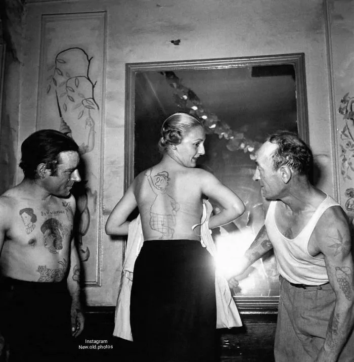 Gente mostrando los tatuajes que han recibido durante un concurso de tatuadores aficionados en Francia, 1950. Foto de Robert Doisneau