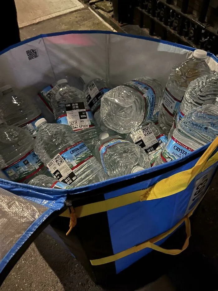 Large bag filled with multiple bottled water containers on the street