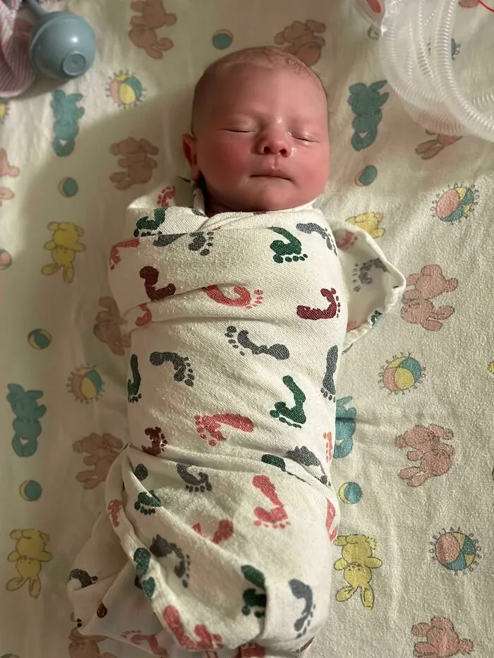 Newborn baby wrapped in a footprint blanket sleeping peacefully, capturing the essence of what it means to be a dad.