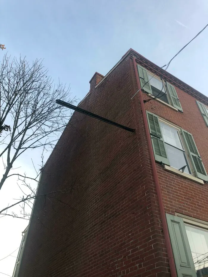 Este poste de una señal quedó encajado a este lado de mi apartamento después de un accidente de un conductor ebrio en mi calle
