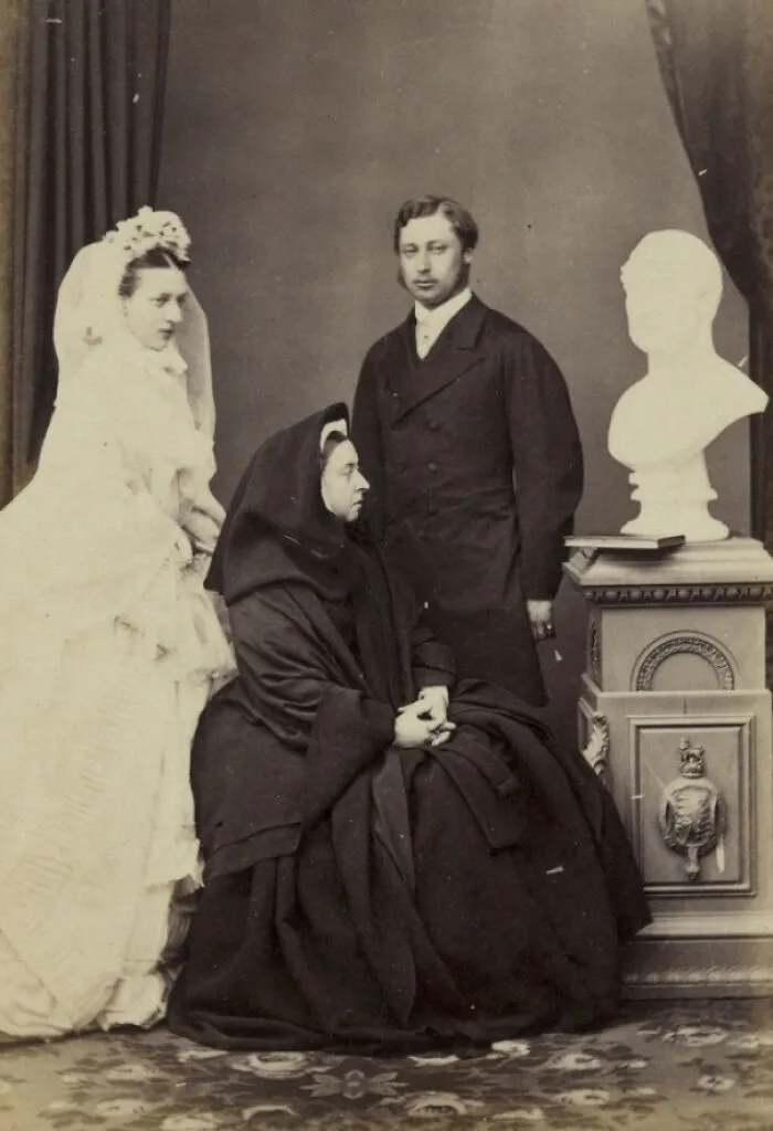 La madre del novio se mete en la foto de los recién casados ​​sentándose entre ellos vestida de luto y mirando fijamente un busto de su difunto marido.