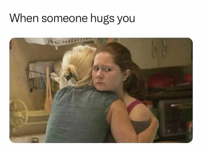 Woman looking uncomfortable while hugging another person, relatable meme about introverts and social awkwardness.