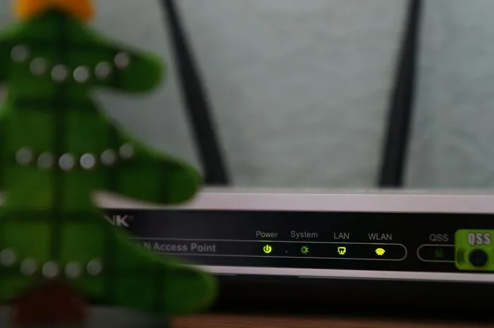 WiFi router with LED indicators, partially obscured by a decorative figurine, representing tech humor in unfortunate names.