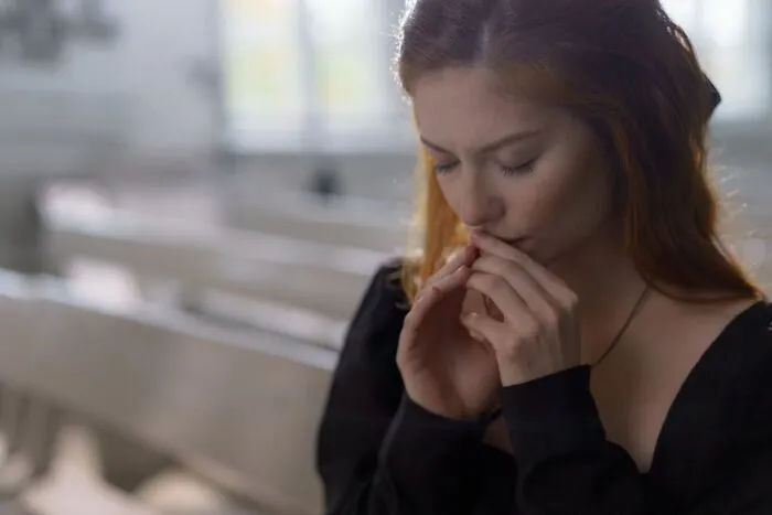 A woman in a black shirt sitting pensively, perhaps pondering unfortunate baby names.
