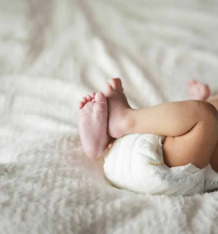 Baby lying on soft blanket, wearing a diaper, highlighting the humorous aspect of unique baby names.