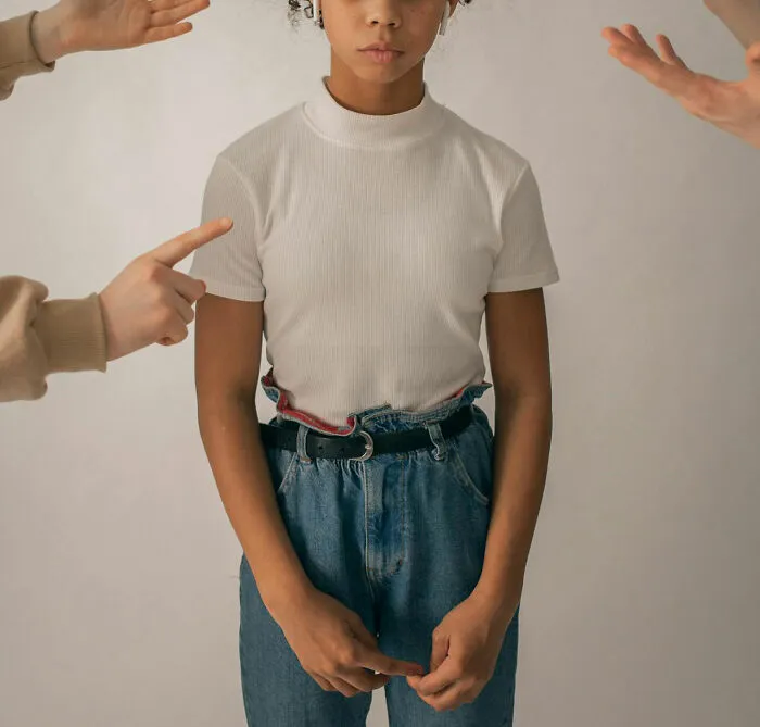 Person standing in a white shirt, surrounded by pointed hands, highlighting unfortunate names theme.
