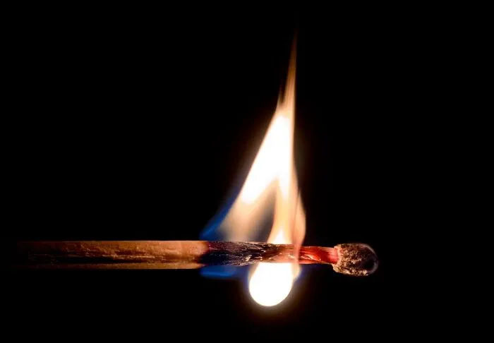 A matchstick burning against a dark background, symbolizing unfortunate names and unexpected outcomes.