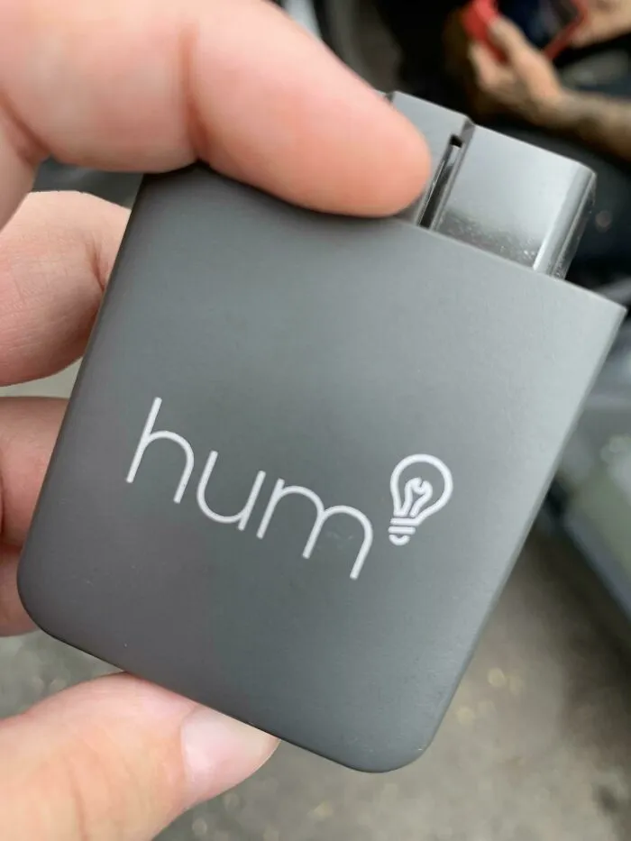 A hand holding a small device labeled "hum" with an oddly terrifying design feature.