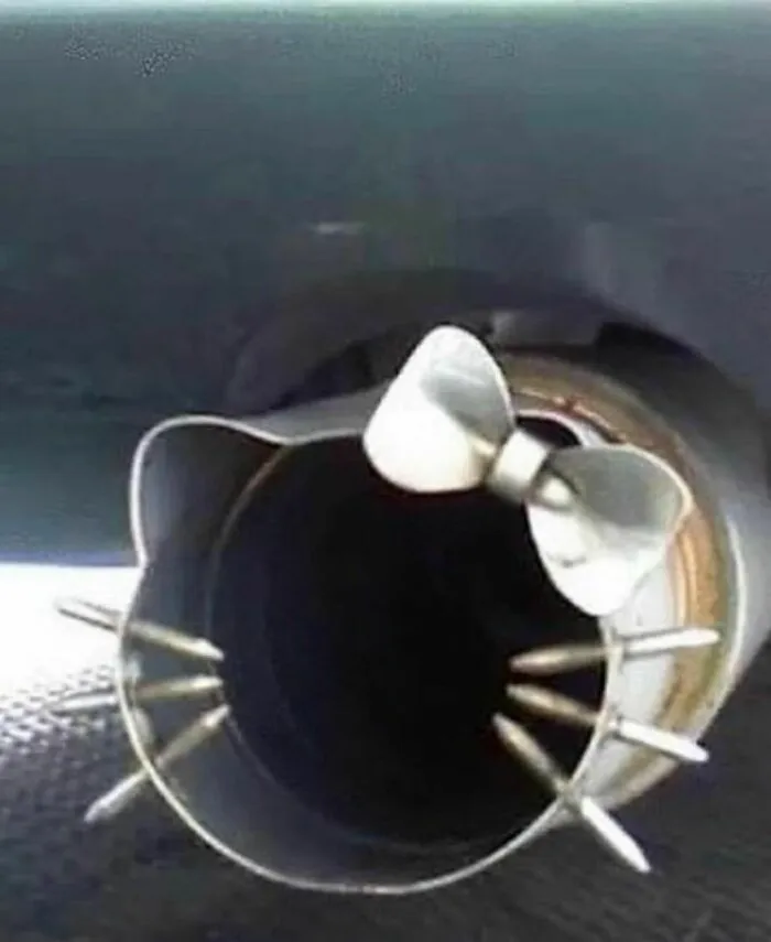 Tubo de escape de coche decorado con forma de gato y un lazo, imagen divertida pero un poco incómoda.