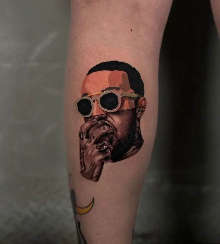 Tattoo on calf merging realism and abstract art styles, depicting a person with sunglasses and hand over mouth.