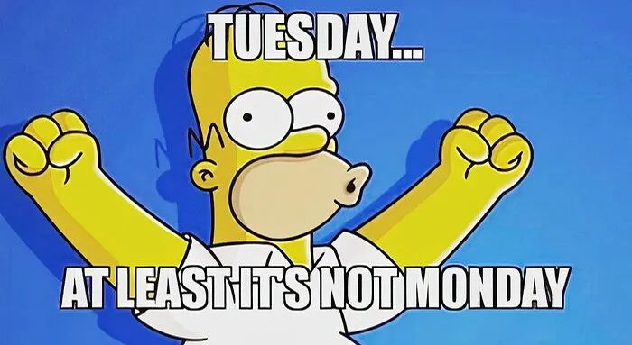 Homer Simpson happily raising fists with text “Tuesday... at least it’s not Monday,” celebrating Tuesday memes humor.
