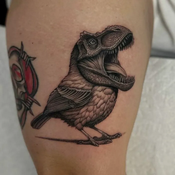 Tattoo of a dinosaur with bird-like features on an arm, showcasing creative dinosaur tattoo ideas.