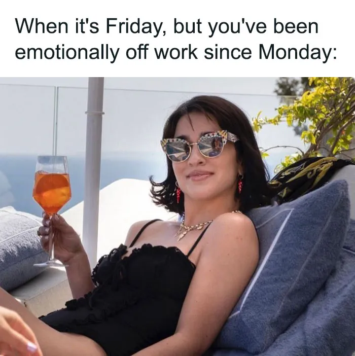 Woman lounging with a drink, wearing sunglasses, embodying a happy Friday vibe.
