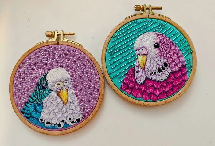 Creative embroidery art of colorful birds in two wooden hoops, showcasing intricate needlework and vibrant designs.