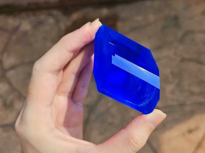 A hand holding a vibrant blue crystal, showcasing one of the weird hobbies people enjoy in their spare time.
