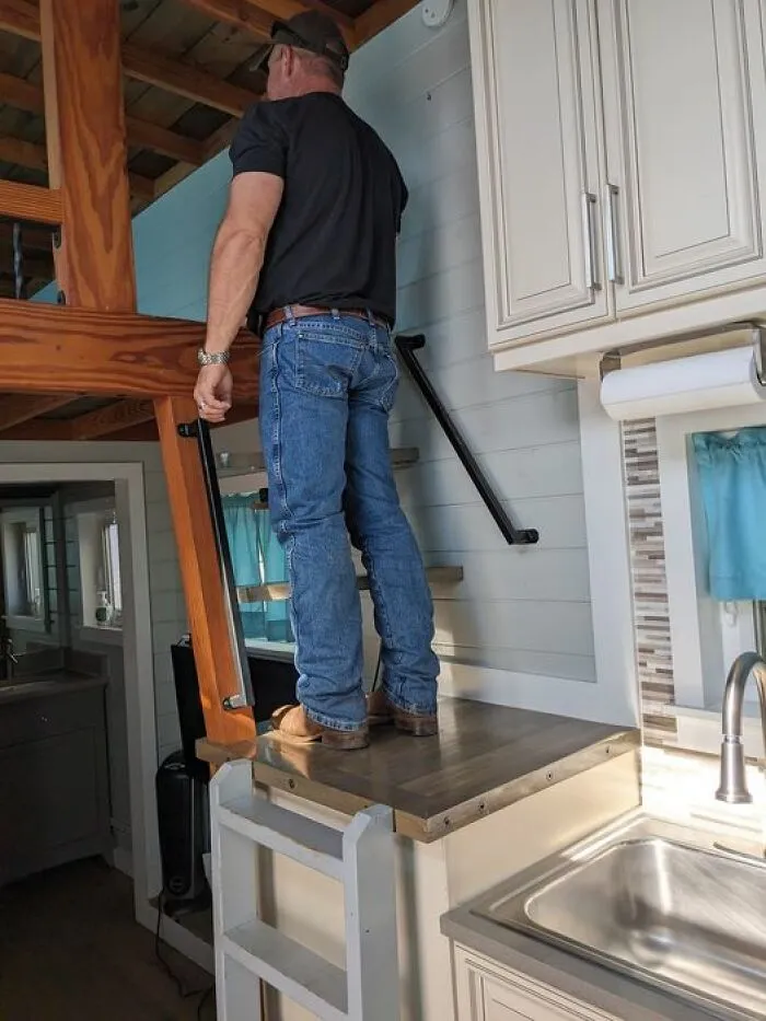 Sube por la escalera hasta la encimera de la cocina y luego sube los escalones hasta el altillo del dormitorio. No importa que la barandilla esté donde están tus pies.