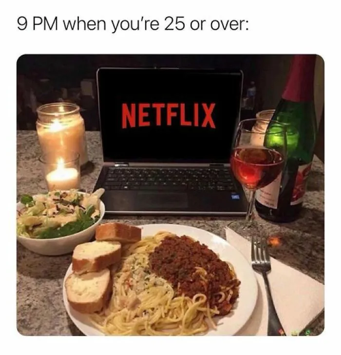 Laptop showing Netflix with a candlelit dinner of pasta and salad, capturing the Netflix meme humor.