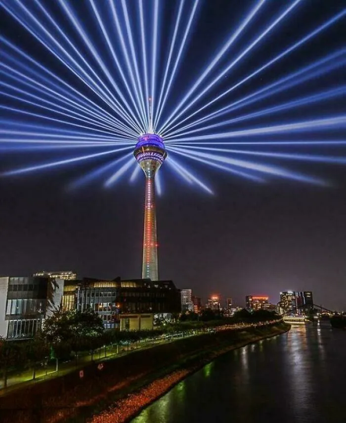 Tower building illuminated at night with beams of light radiating, evoking an evil aura like a supervillain headquarters.