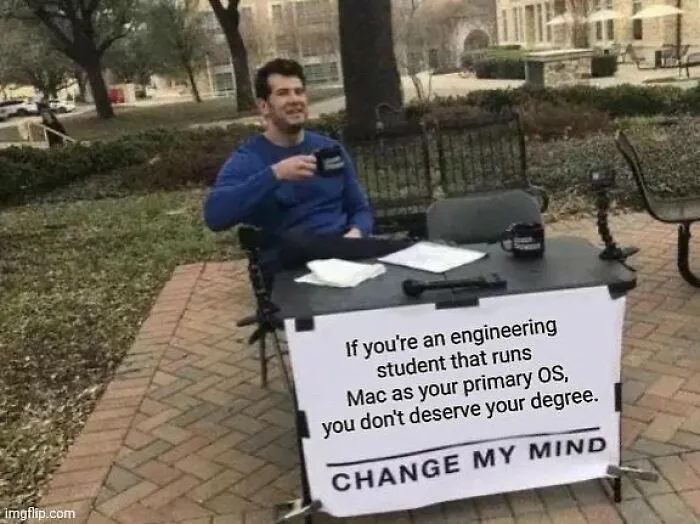 Man enjoying coffee at a table with a sign challenging engineering students using Mac as their primary OS.