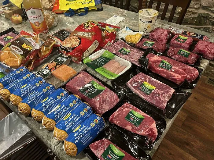 Groceries from dumpster diving, including meat, cheese, and snacks, arranged on a kitchen countertop.