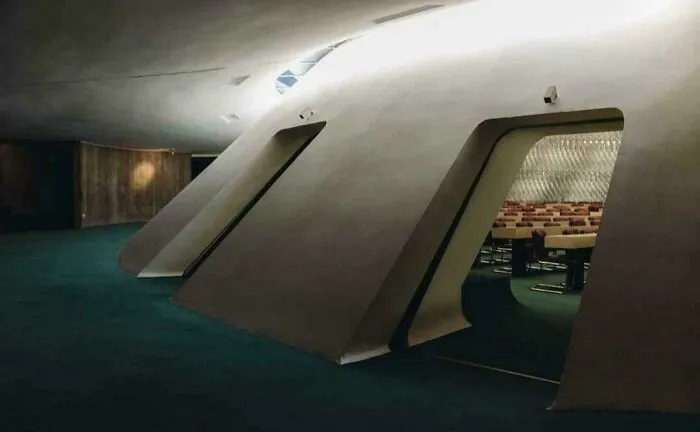 Dark futuristic building interior with angular walls and empty chairs, evoking evil auras like a supervillain headquarters.