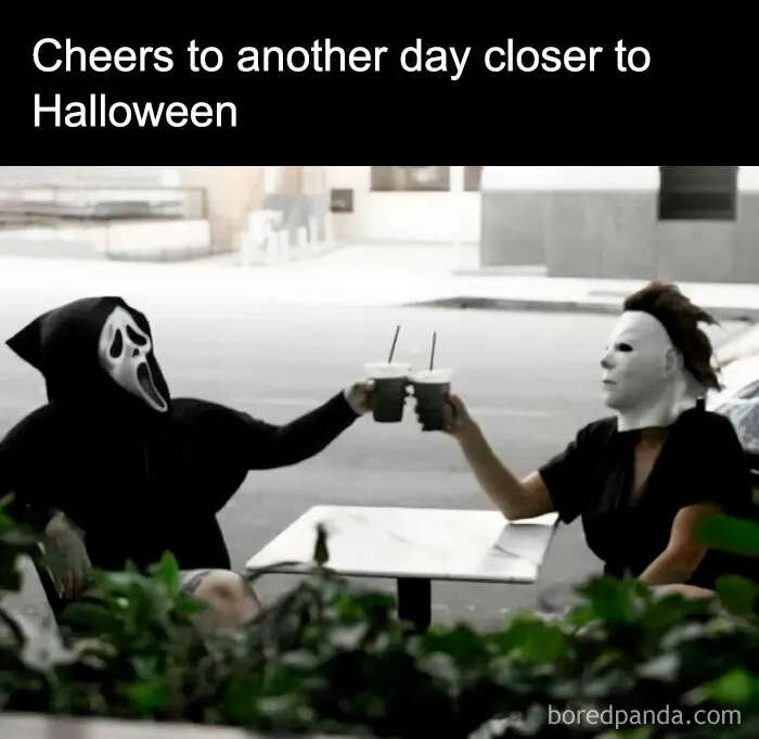 Two people in Halloween costumes toast with coffee, celebrating the season with humor.