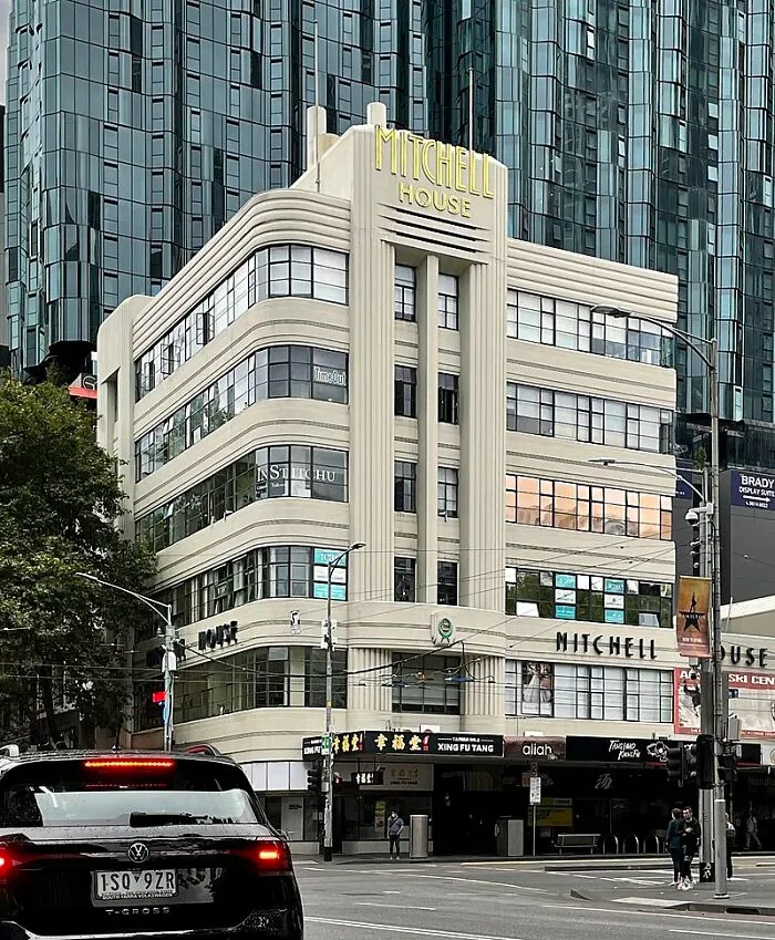Intricate Art Deco doors and architecture on Mitchell House, a historic building in a bustling city intersection.