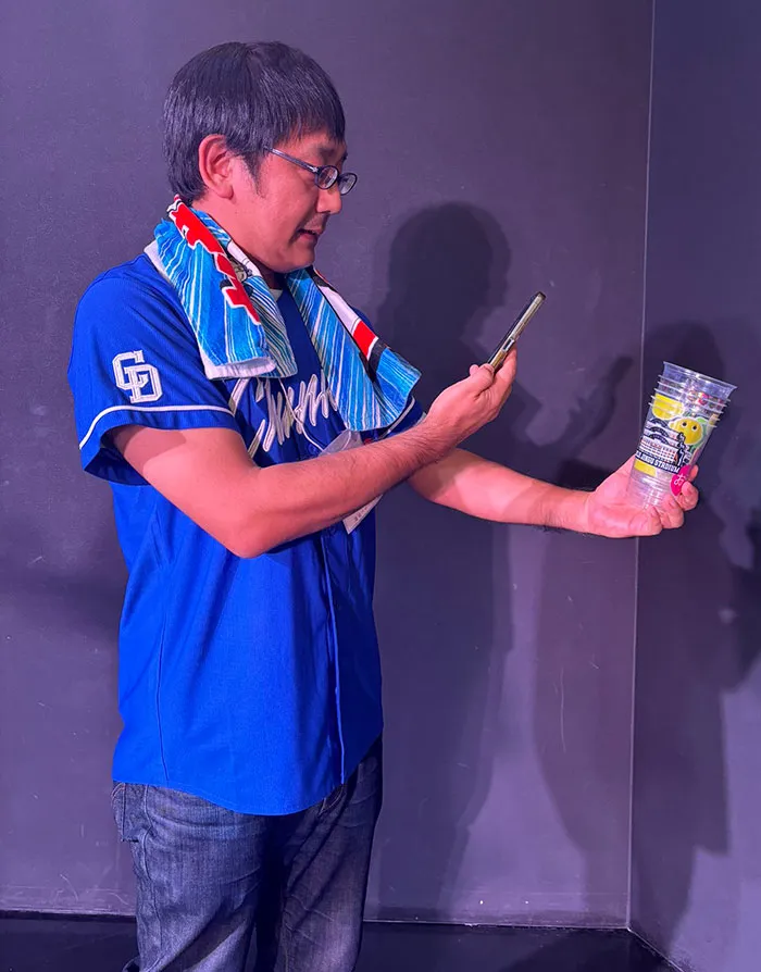 An Old Man Taking A Photo Of The Cup He Used At The Stadium