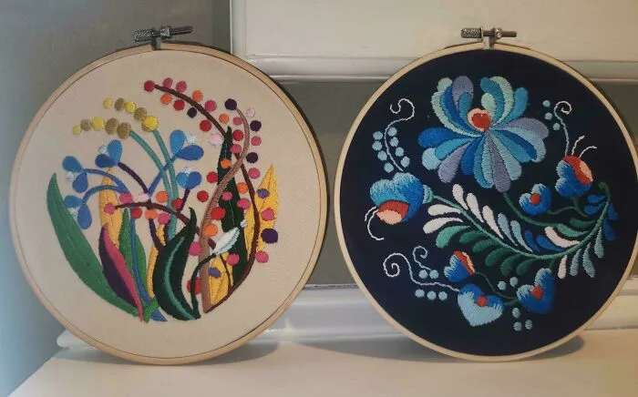 Two colorful embroidery designs in wooden hoops, showcasing detailed floral and abstract stitch patterns on fabric.