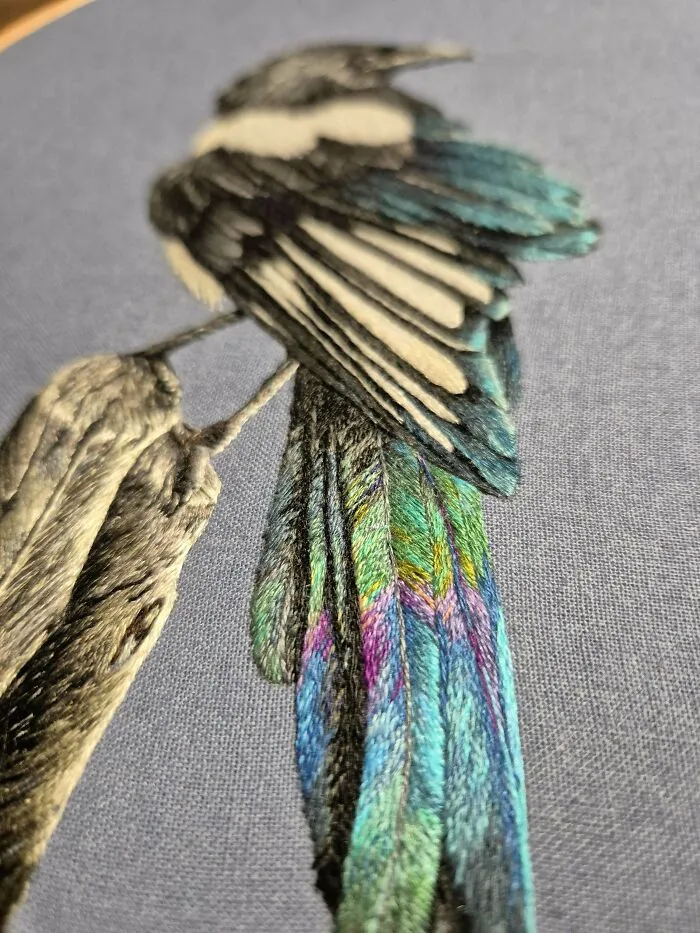 Close-up of a colorful bird embroidery design on fabric showcasing beautiful embroidery details and vibrant threads.