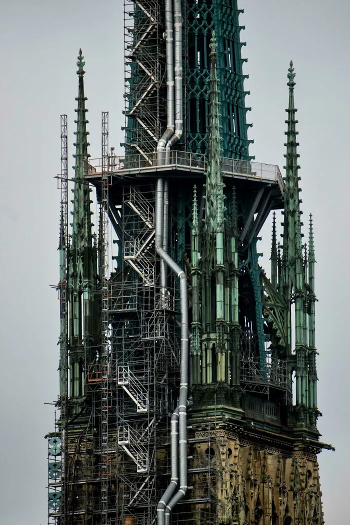 Gothic building under renovation with scaffolding and pipes, exuding an evil aura like a supervillain headquarters.