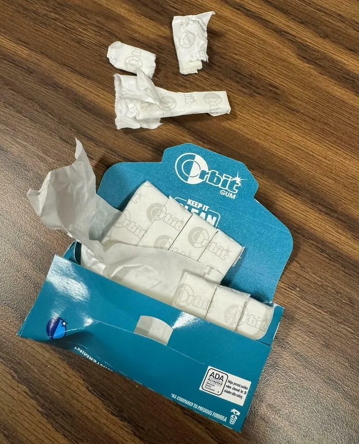 Partially empty Orbit gum pack placed messily on a wooden table, illustrating mildly infuriating disorder.
