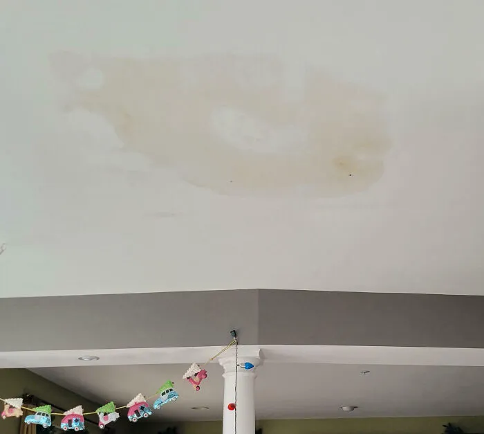 Ceiling stain from a home improvement fail, with decorative train bunting below.