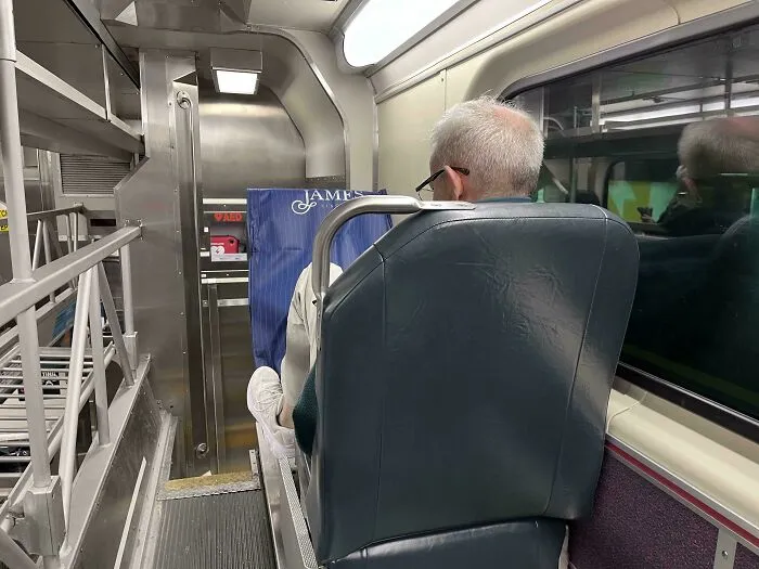 Passenger on public transport taking up space with a shopping bag, viewed from behind.