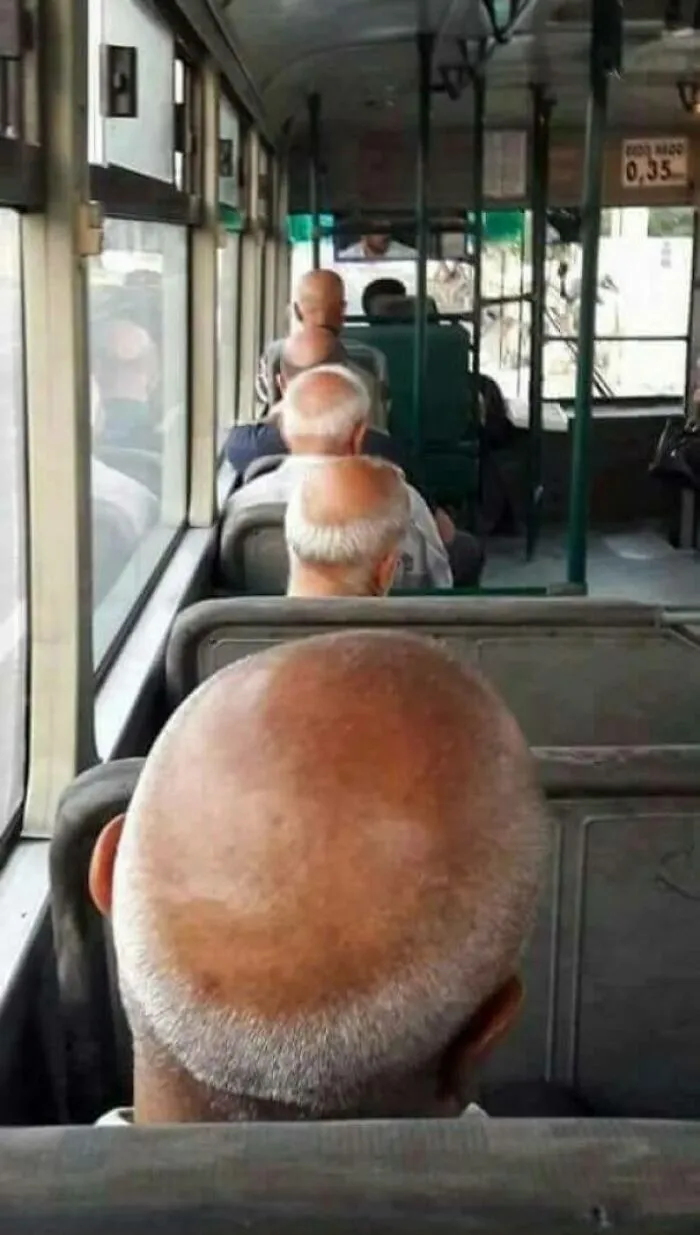 Bald men on a bus appear as uncanny doppelgangers, creating a visual glitch in the Matrix.