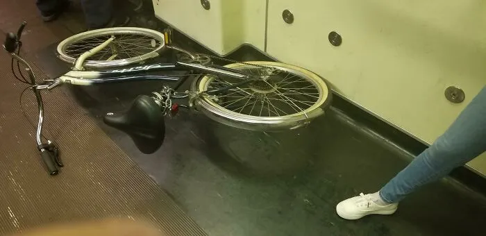 Public transport passenger with a bicycle blocking the aisle, causing inconvenience.