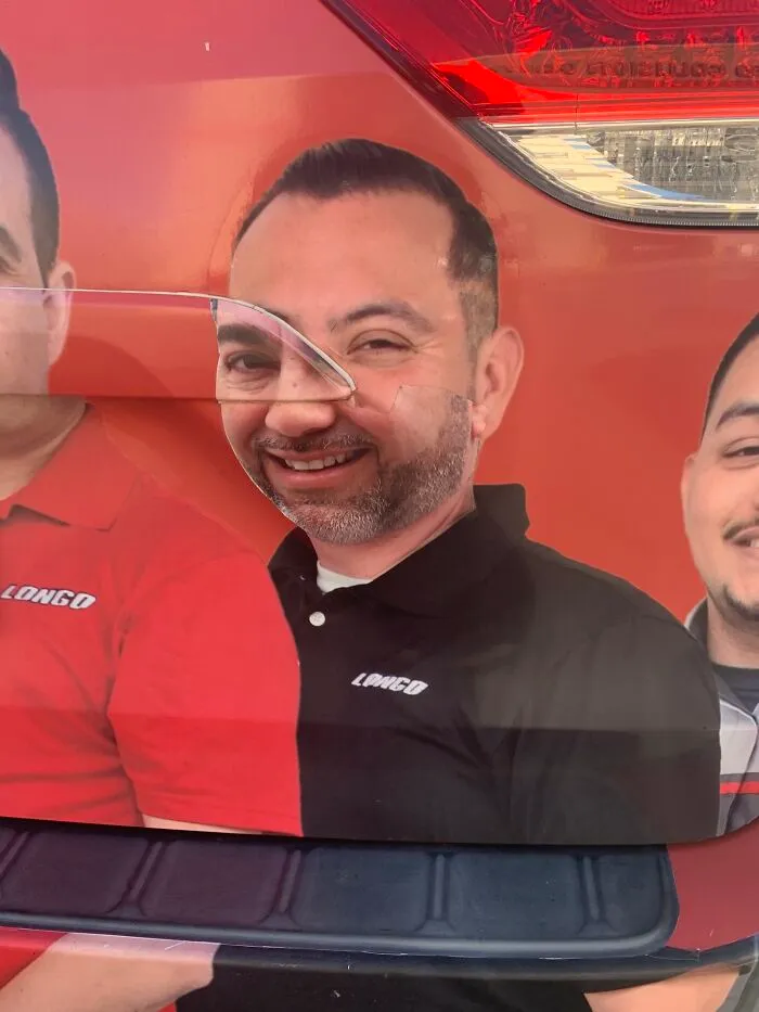 Humorous ad fail with a misaligned car wrap showing a man's face distorted by a trunk seam.