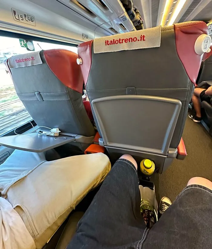 Cramped seating on public transport with passengers in casual attire, showing limited legroom space.