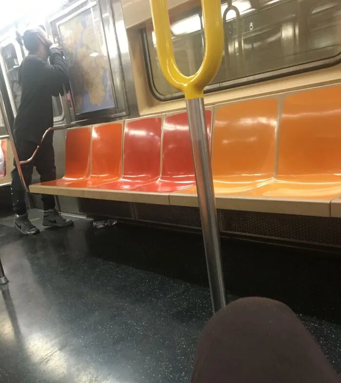 Public transport passenger standing closely to a subway map on an empty train.
