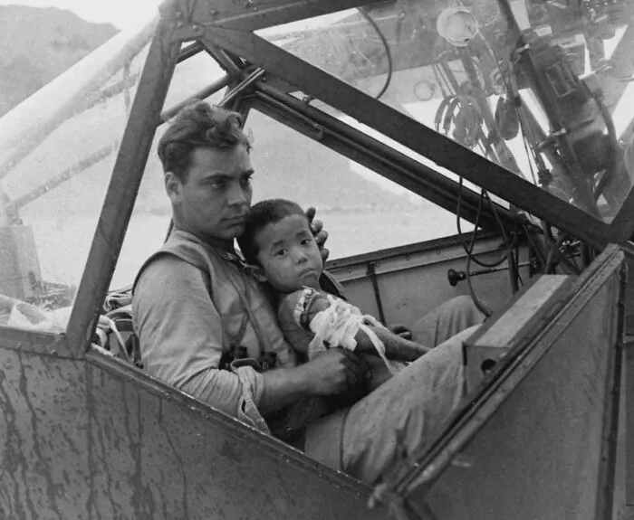 A U.S. Serviceman Shelters A Young Injured Japanese Boy From The Rain In Saipan In July, 1944