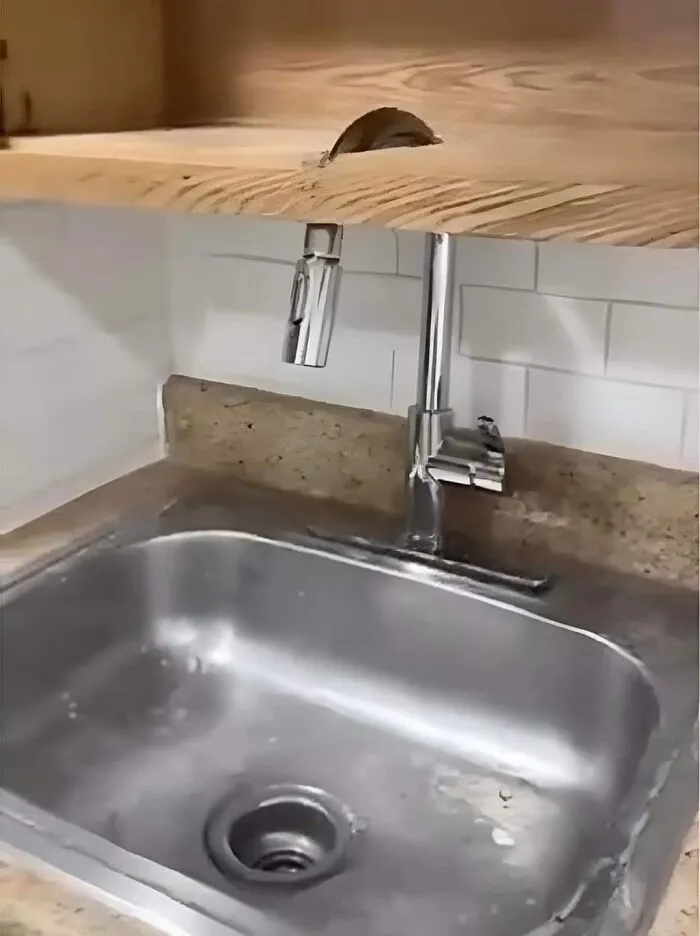 Engineering fail: faucet installed under a wooden countertop, making it unusable.